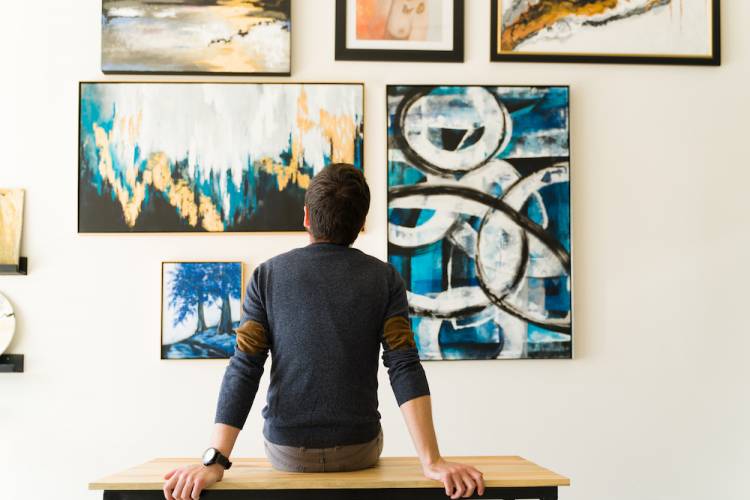 person sitting and looking at paintings in a gallery