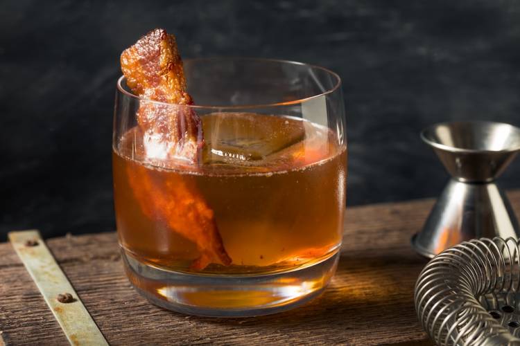 glass of bourbon with a slice of bacon in it