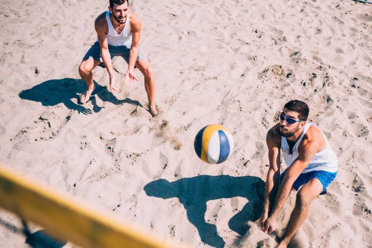 two men playing in sand volleyball court